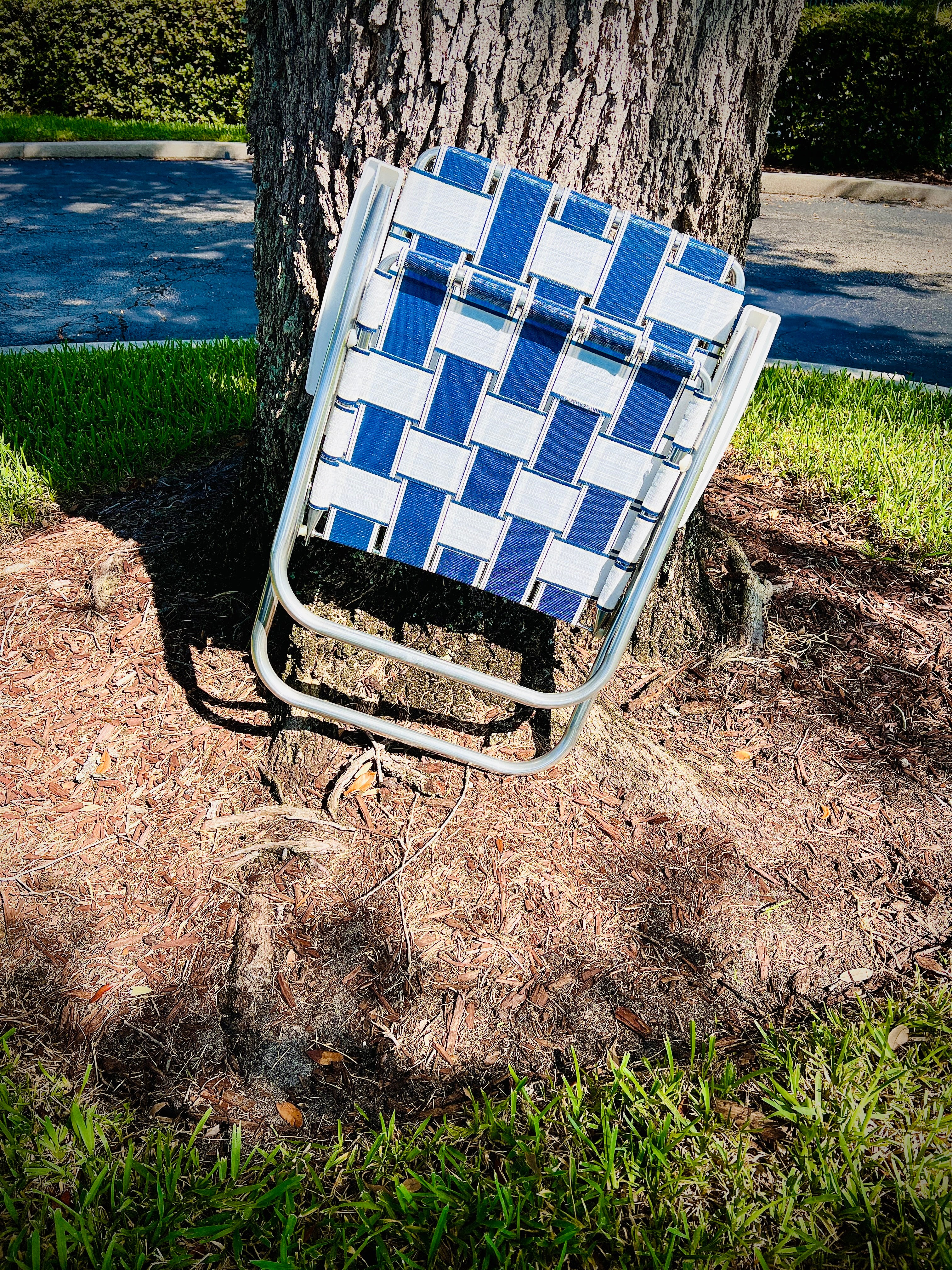 St. Augustine Classic Chair Lawn Chair USA Aluminum Webbing Chair Sitting Outside Folded up by oak tree